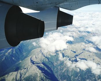 Cropped image of airplane flying above mountains