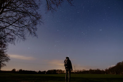 Rear view of silhouette woman standing on field against sky at night