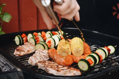 Hand of person preparing food on barbecue grill