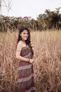 Portrait of smiling young woman standing against grass