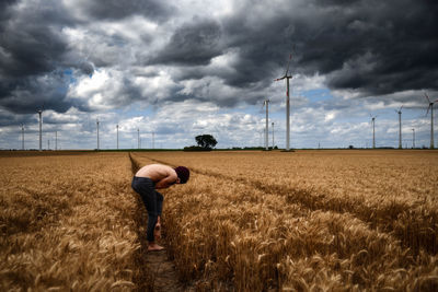 Rear view of man standing on field against sky