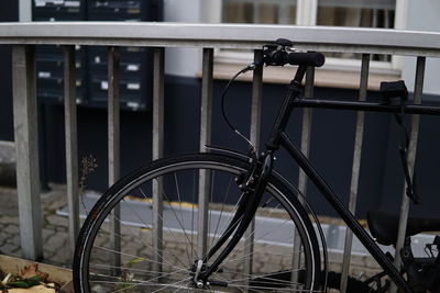 Close-up of bicycle parked by railing in city