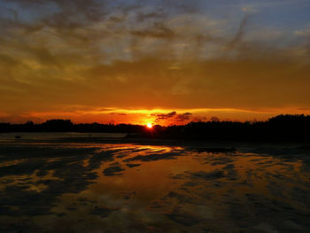 Scenic view of sea against dramatic sky during sunset