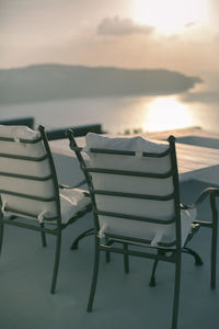 Empty chairs on beach against sky