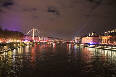 Illuminated bridge over river against sky at night