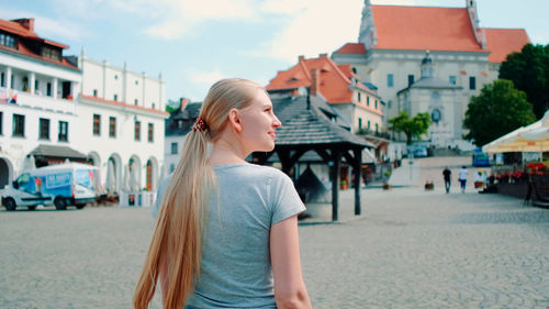 Side view of young woman standing on street in city