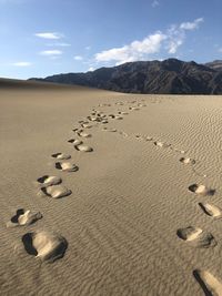 Footprints on sand at beach against sky
