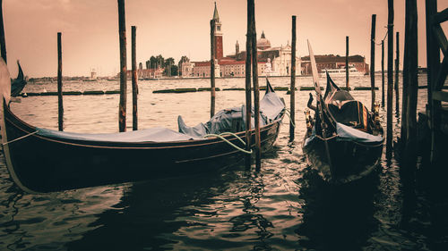 Gondolas moored in grand canal by doges palace against sky