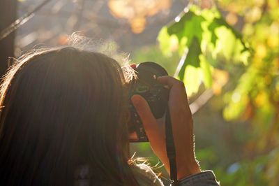 Rear view of woman photographing outdoors