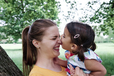 Girl biting mother's nose at park