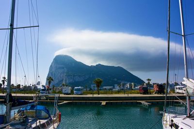 Sailboats moored at harbor against sky