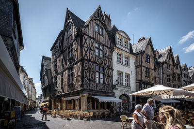 People on city street by buildings against sky