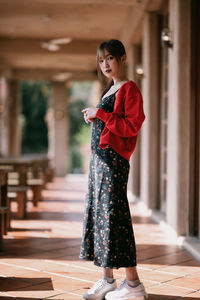 Side view of young woman standing against building