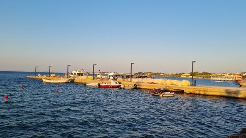 Sailboats moored in sea against clear sky