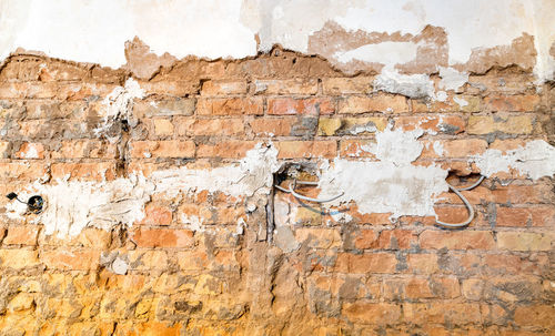 Brick wall with holes for power sockets and cables during a renovation as a background