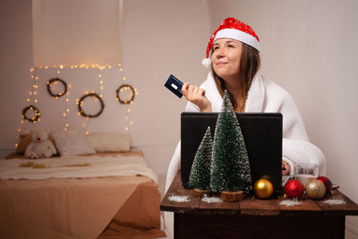 Smiling woman holding credit card while sitting at table