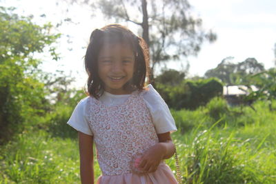 Portrait of smiling girl standing on grassy field