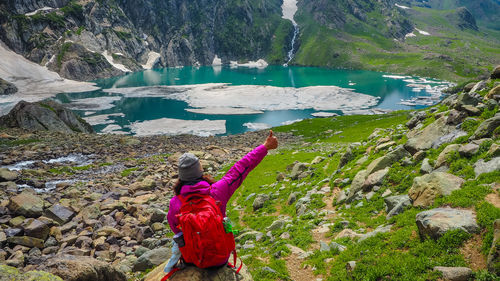 Rear view of woman standing on rock by lake