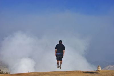 Rear view of man standing against sky