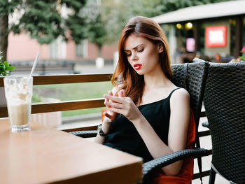 Young woman drinking glass on table at restaurant