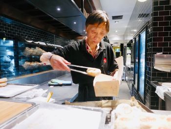 Young woman preparing food in kitchen at store