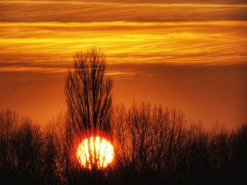 Scenic view of silhouette field against orange sky