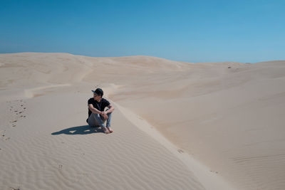 Full length of man on sand dune in desert against sky