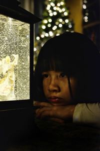 Close-up of thoughtful girl looking away while leaning on table