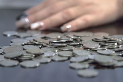 Close-up of hand by coins on table