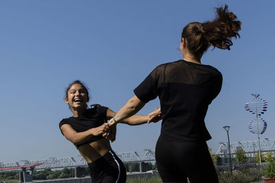 Mom and daughter in sportswear on a sunny summer day on the embankment in the park