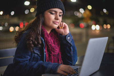 Young woman using mobile phone at night