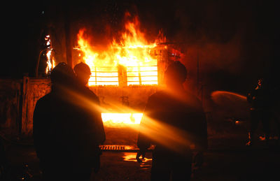 Rear view of silhouette people against fire in the dark