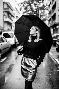 Young woman standing on street in rain