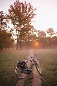 Bicycle on field against sky during sunset