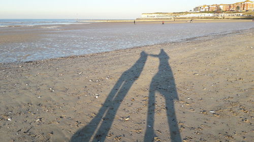 Shadow of people on beach against sky