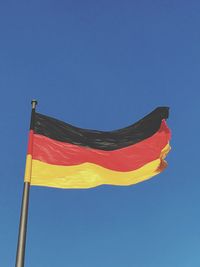 Low angle view of flag against clear blue sky