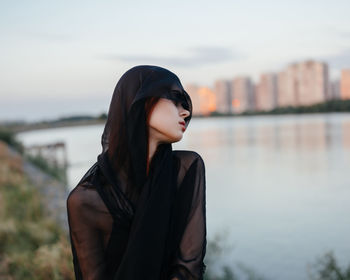 Beautiful woman standing by lake against sky