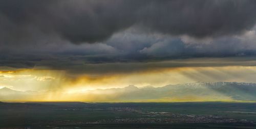 Scenic view of landscape and mountains against cloudy sky during sunset