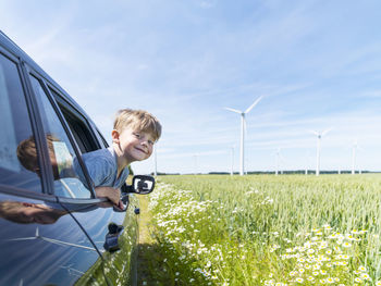 Smiling boy in car near wind turbines