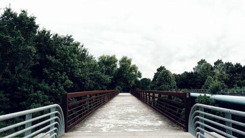 Footbridge over trees against sky