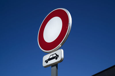 Low angle view of road sign against clear blue sky