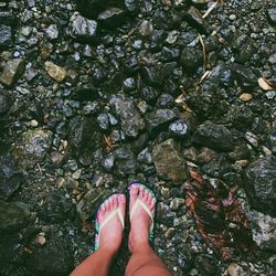 Low section of woman standing on wet rocks