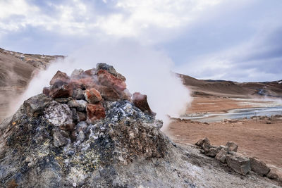 Steaming fumarole in geothermal area of hverir at namafjall against cloudy sky