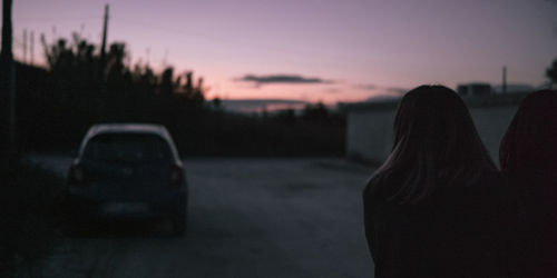 Rear view of silhouette woman standing against sky during sunset