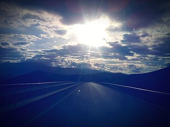 Aerial view of road amidst landscape against bright sun