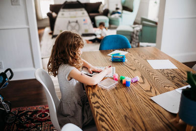 Young girl coloring picture while sitting at dining room table