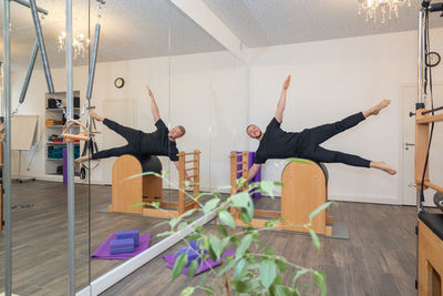 Male fitness pilates trainer shows exercises on special simulators. pilates stretch tables