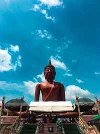 Low angle view of buddha statue against blue sky