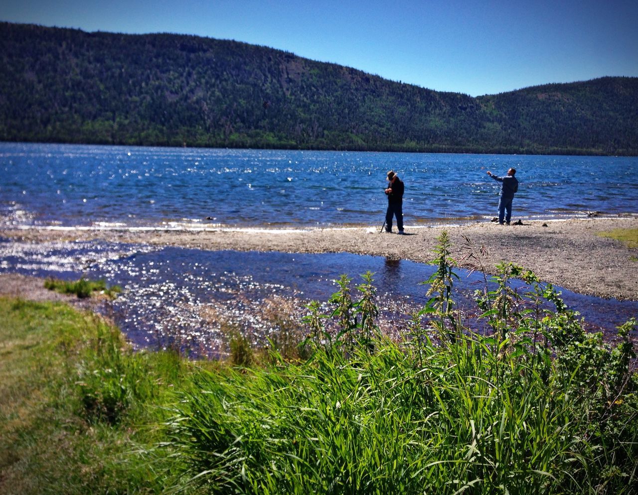 mountain, water, leisure activity, lifestyles, tranquil scene, beauty in nature, tranquility, scenics, lake, nature, men, mountain range, grass, clear sky, rear view, sky, person, plant