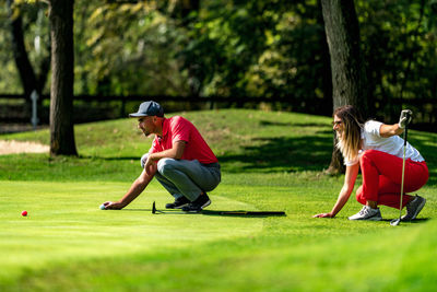 Young couple on a golf course, reading green